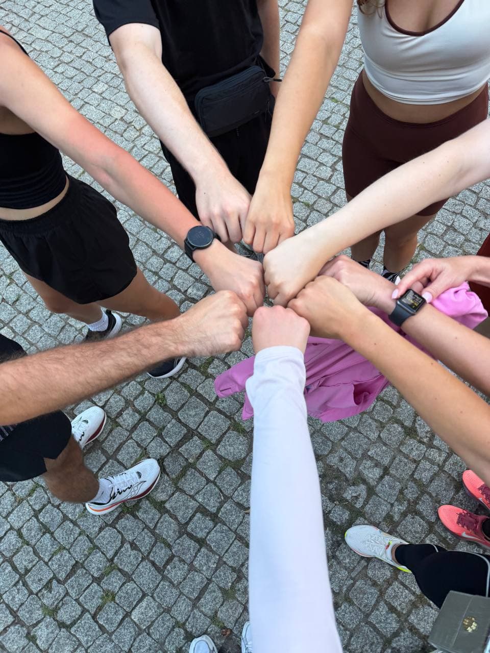 Runners forming a fist-bump circle after training