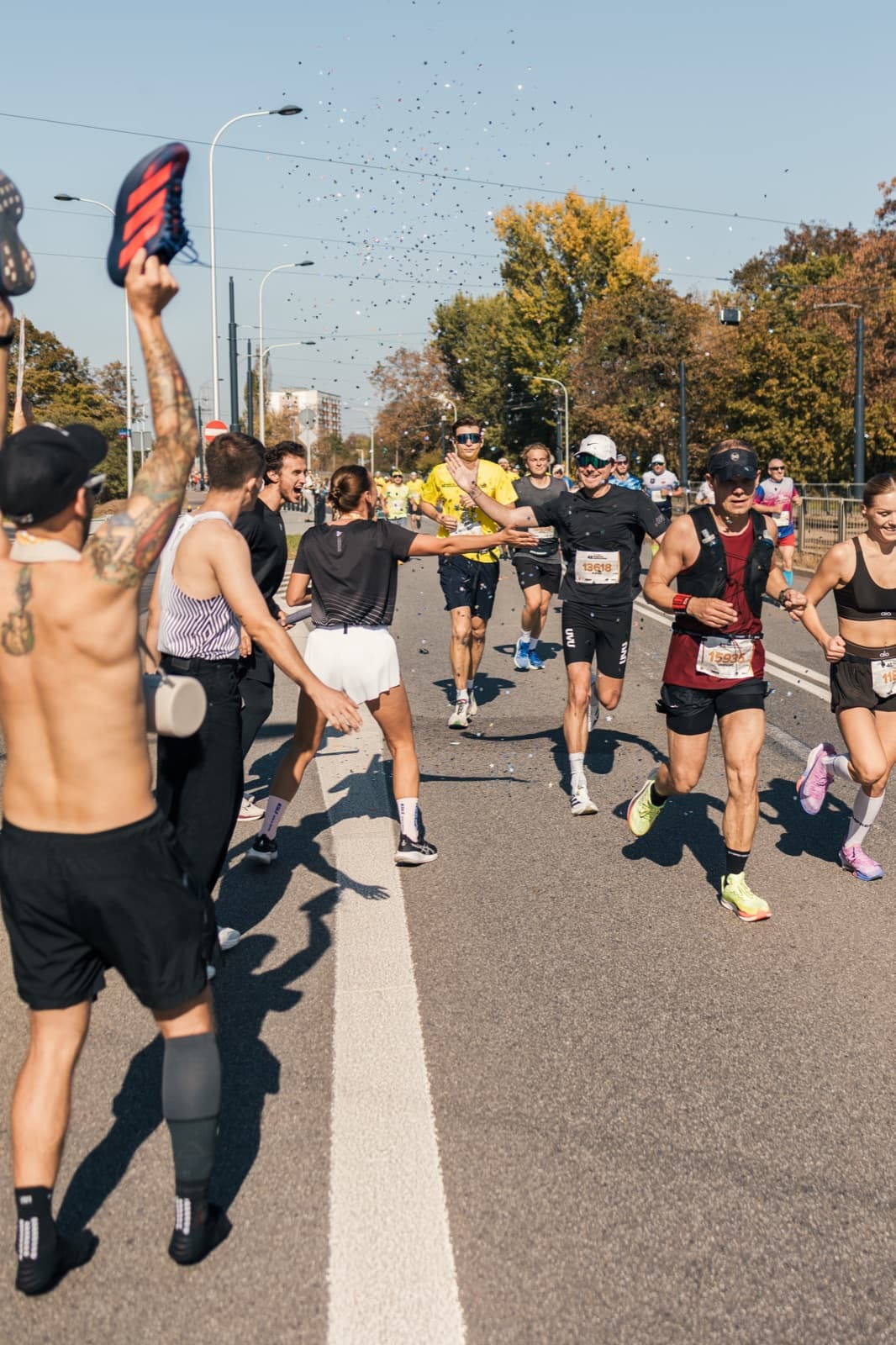 Runners racing past cheering supporters on a sunny marathon course